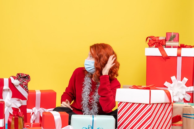 Free Photo front view young woman sitting around xmas presents in mask on yellow