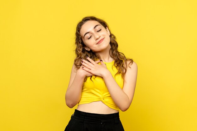 Front view of young woman smiling on the yellow wall