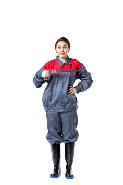 front view of young woman in special uniform holding hacksaw on white wall