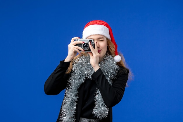 Free photo front view of young woman taking photo with camera on blue wall