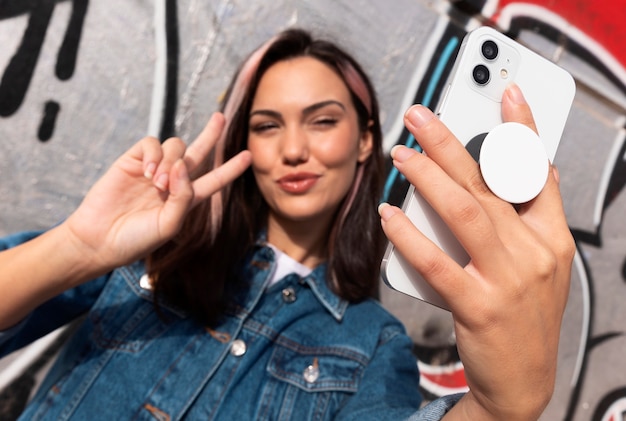 Free photo front view young woman using popsocket