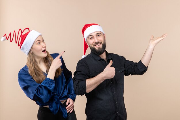 Front view of young woman with man expressing different emotions on pink wall