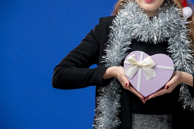 Front view of young woman with New Year's present on a blue wall