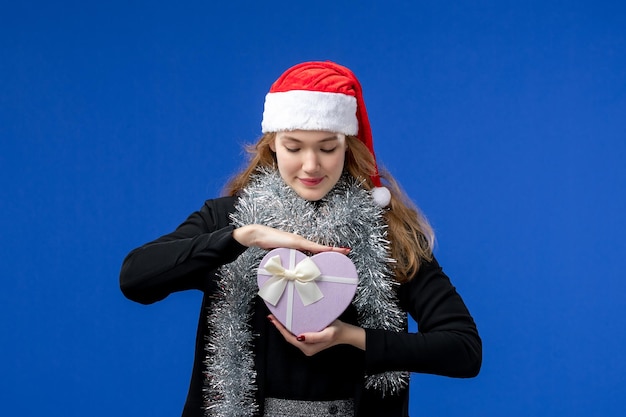 Free photo front view of young woman with new year's present on blue wall