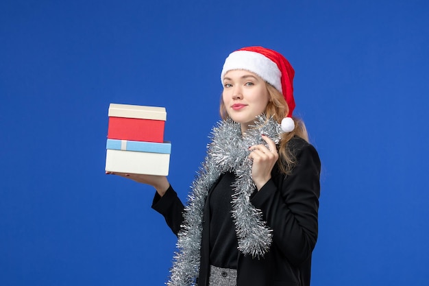 Free photo front view of young woman with new year's presents on blue wall