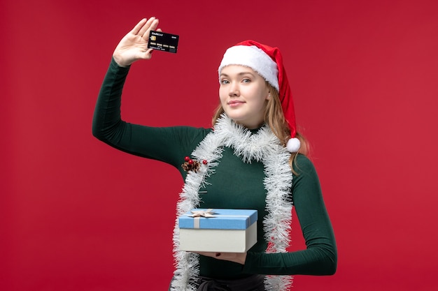 Front view young woman with present and bank card on red background