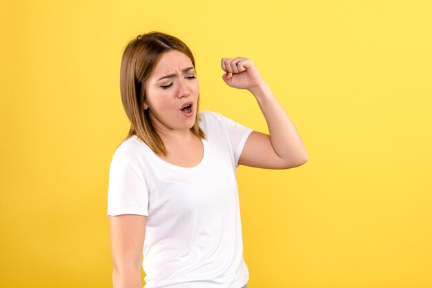 Front view of young woman on yellow wall