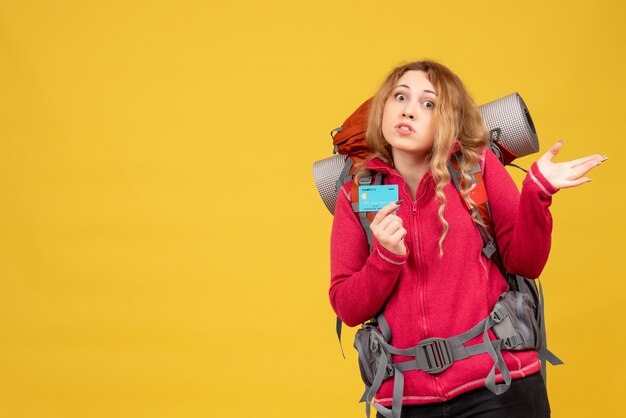 Front view of young worried travelling girl in medical mask holding bank card