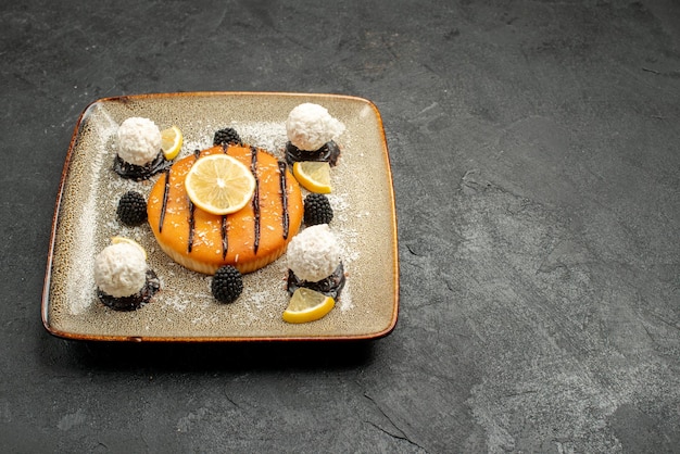 Free photo front view yummy cake dessert with lemon slices and coconut candies on dark background pie dessert sweet cake candy tea