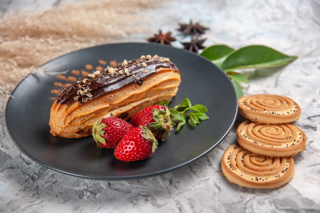 Front view yummy choco eclairs with cookies on light table biscuit cake dessert cookie