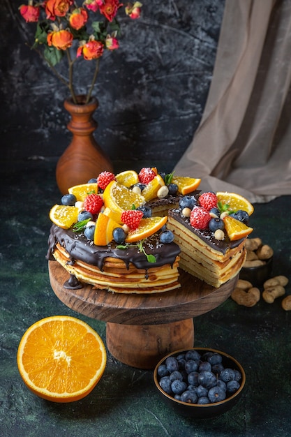 Front view yummy chocolate cake with fruits on dark wall