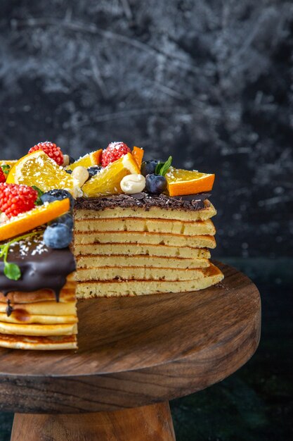 Front view yummy chocolate cake with fruits on dark wall