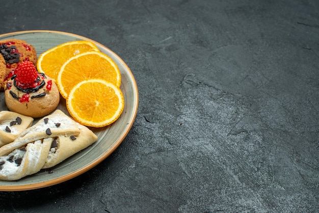 Front view yummy cookies with fruity pastries and orange slices on a dark surface fruit sweet cake pie tea sugar