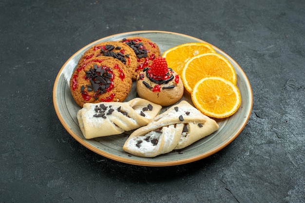 Front view yummy cookies with fruity pastries and orange slices on dark surface fruit sweet cake pie tea sugar