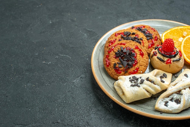 Front view yummy cookies with fruity pastries and orange slices on dark surface fruits sweet cake pie tea sugar