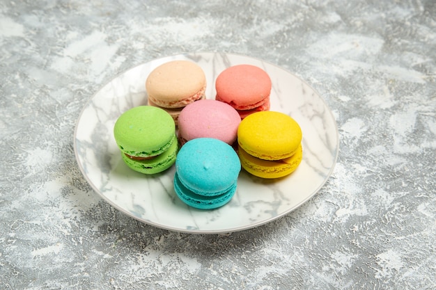 Front view yummy french macarons colorful cakes inside plate on the white surface cake sugar biscuit sweet pie cookies