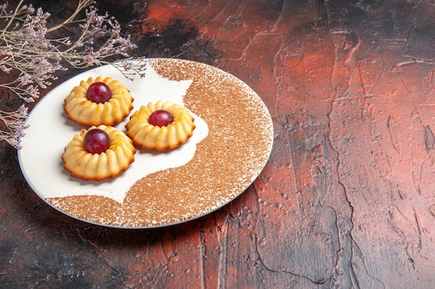 Front view yummy little cookies inside plate on a dark table cake sweet biscuits