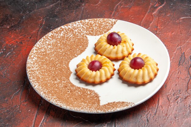 Front view yummy little cookies inside plate on dark table sweet biscuit cake