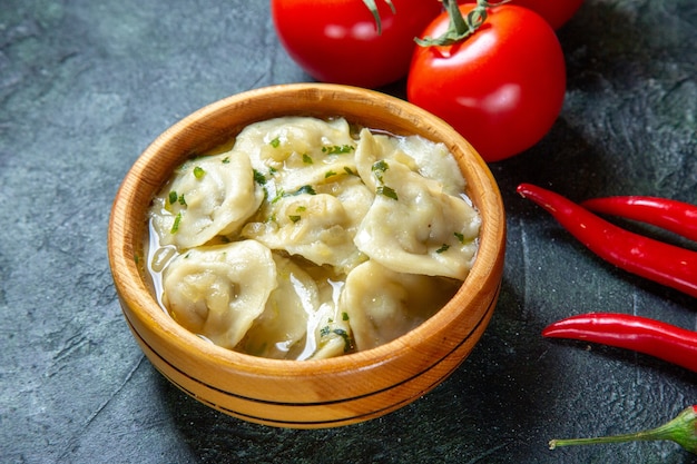 Front view yummy meat dumplings inside wooden plate with fresh tomatoes on dark surface