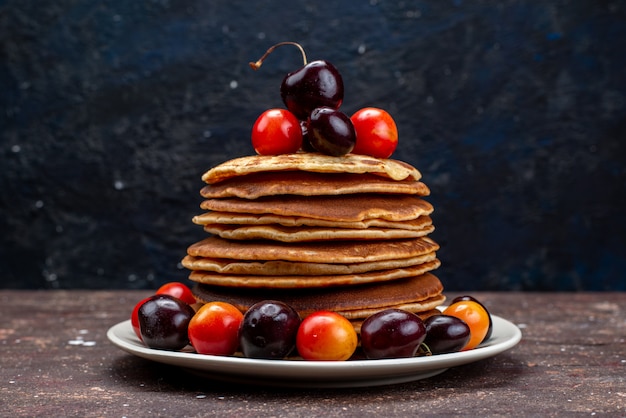 A front view yummy pancakes with cherries inside white plate on the dark desk fruit pancake