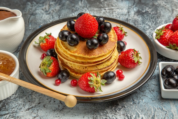 Front view yummy pancakes with fresh fruits and honey on light surface fruit cake sweet