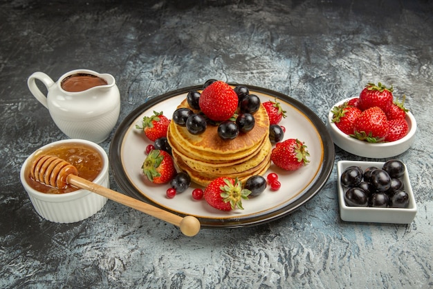 Front view yummy pancakes with fresh fruits and honey on light surface fruits sweet cake