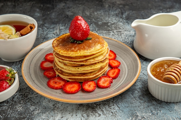 Front view yummy pancakes with fruits and honey on light surface sweet cake fruits