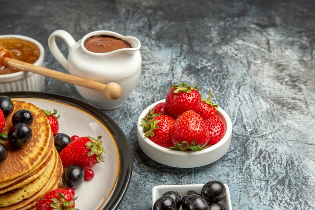 Front view yummy pancakes with honey and fruits on light surface fruit cake sweet