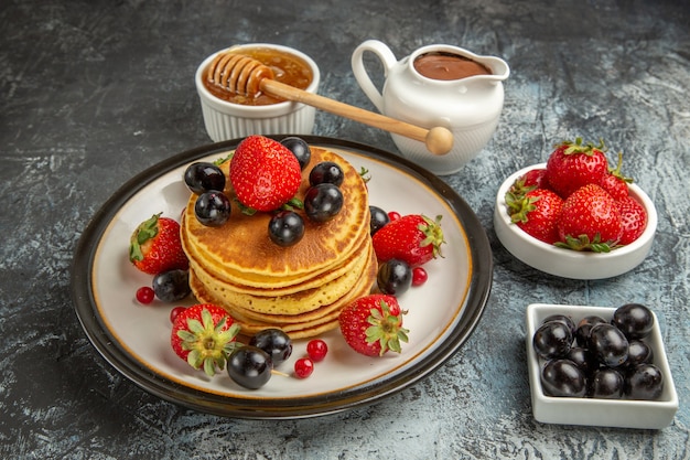 Front view yummy pancakes with honey and fruits on light surface sweet fruit cake