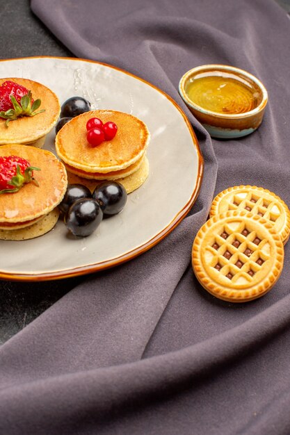 Front view yummy pancakes with olives and fruits on a dark surface sweet fruit cake