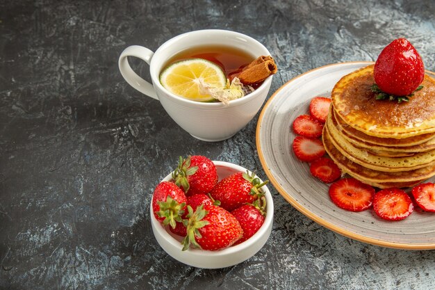 Front view yummy pancakes with tea and fruits on light surface fruit cake sweet