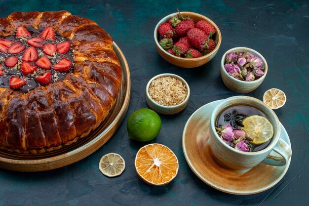 Front view of yummy strawberry pie with cup of tea on dark-blue desk