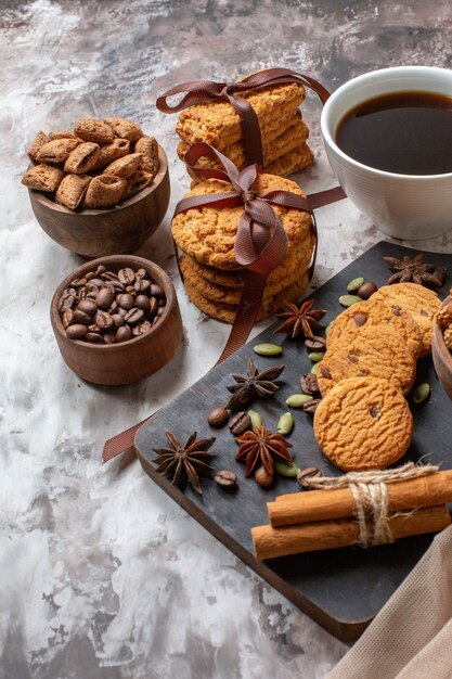 Front view yummy sweet biscuits with coffee seeds and cup of coffee on a light background color cocoa sugar tea cookie sweet cake pie