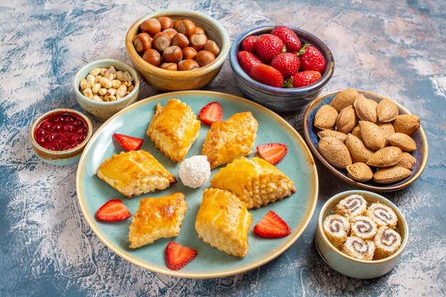 Front view of yummy sweet cakes with fruits and nuts on blue surface