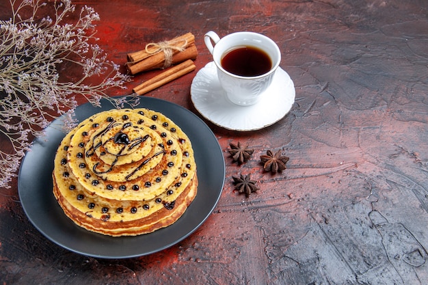 Front view yummy sweet pancakes with cup of tea on dark background cake milk sweet dessert