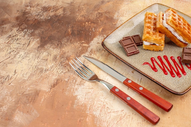 Front view yummy waffle cakes with chocolate bars on brown background