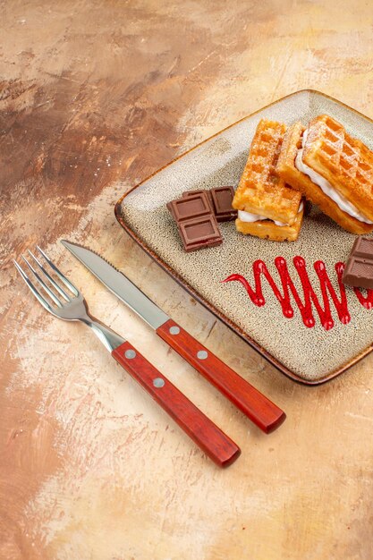 Front view yummy waffle cakes with chocolate bars on brown desk