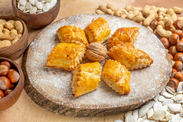 Front view yummy walnut pastries with nuts on light table pie cake sweet pastry