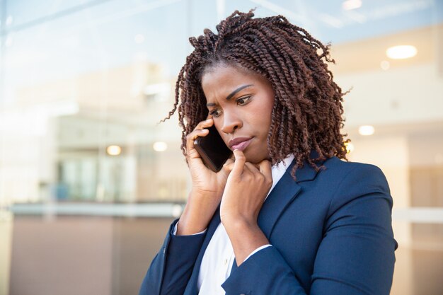 Frowning concerned manager speaking on cellphone