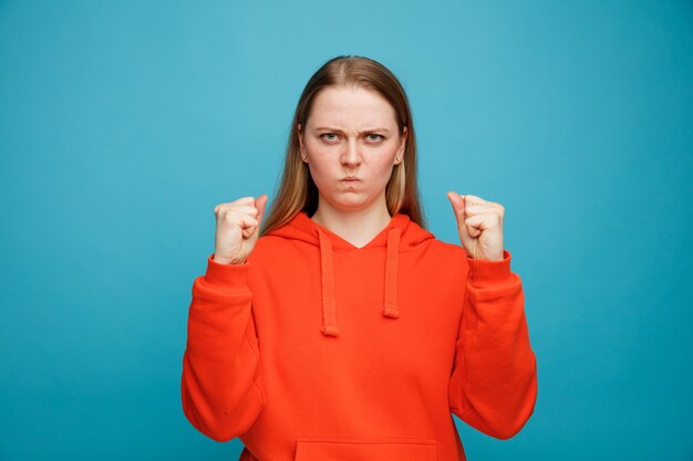 Frowning young blonde woman doing be strong gesture 