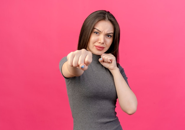 frowning young pretty woman doing boxing gesture at front