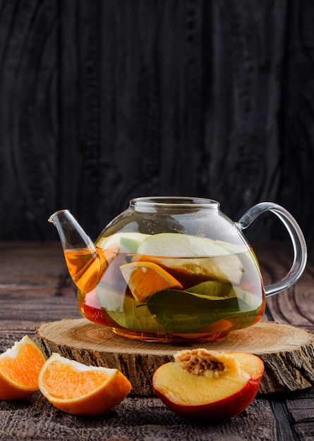 Free Photo fruit infused water with fruits, wood in teapot on stone tile and wooden surface