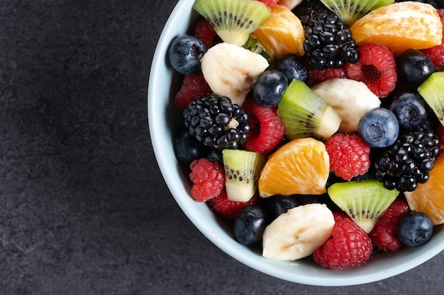 Free photo fruit salad in a blue bowl on black background