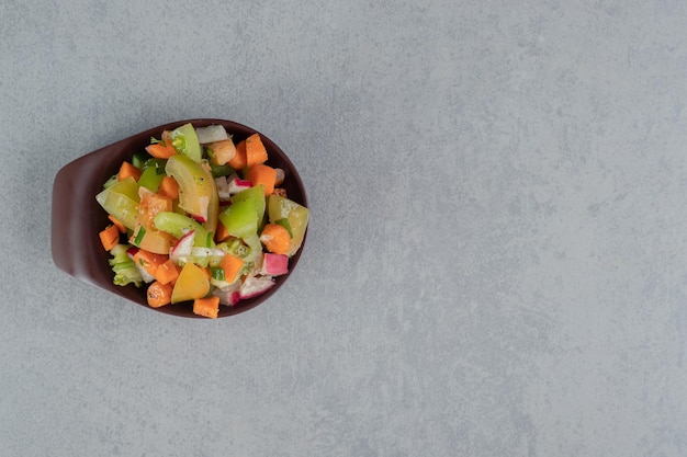 Fruit salad in a brown cup on concrete table.