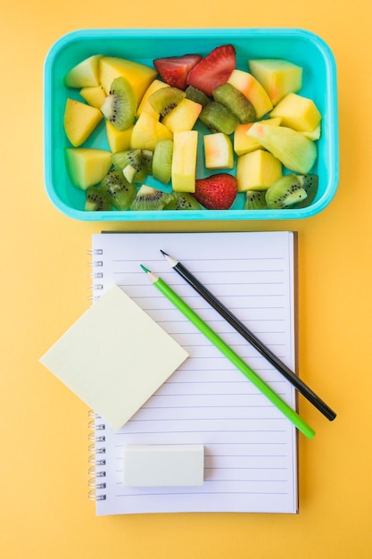 Fruit salad lying near stationery