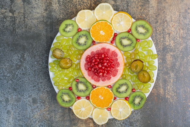 Fruit salad with pomegranate, grapefruit and kiwi on white plate. High quality photo