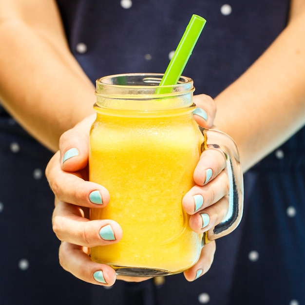 Free photo fruit smoothie healthy eating concept close up of detox smoothie with mango woman hand holding smoothies