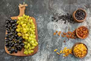 Free photo fruits colorful dried fruits green and black grapes on the cutting board