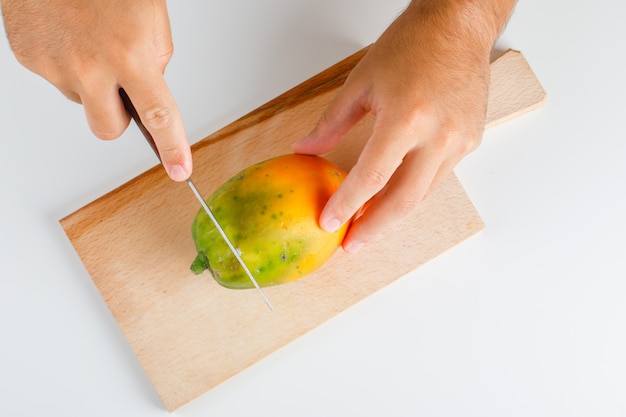 Free photo fruits concept flat lay. hands cutting papaya on wooden board.