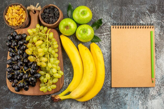 fruits grapes dried fruits bananas three apples cream notebook and green pencil